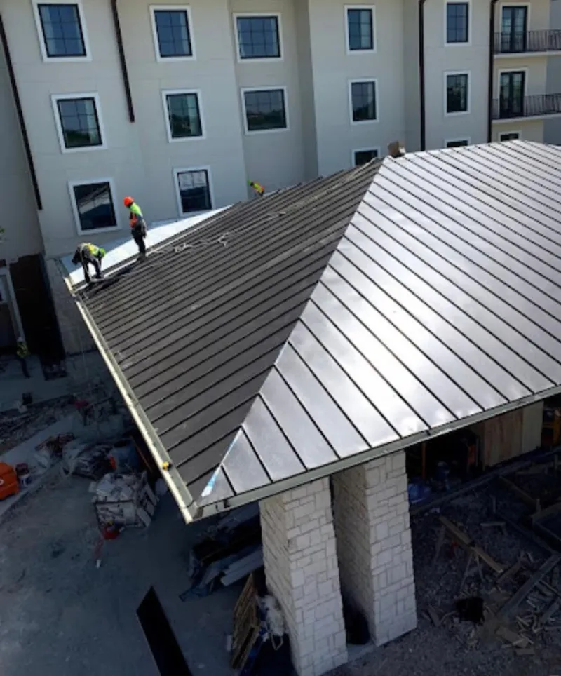 Crew installing standing seam metal roof panels on a commercial project in Fallsburg